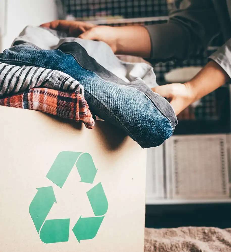 Zu recycelnde Wäschestücke in Karton mit Recycling-Logo