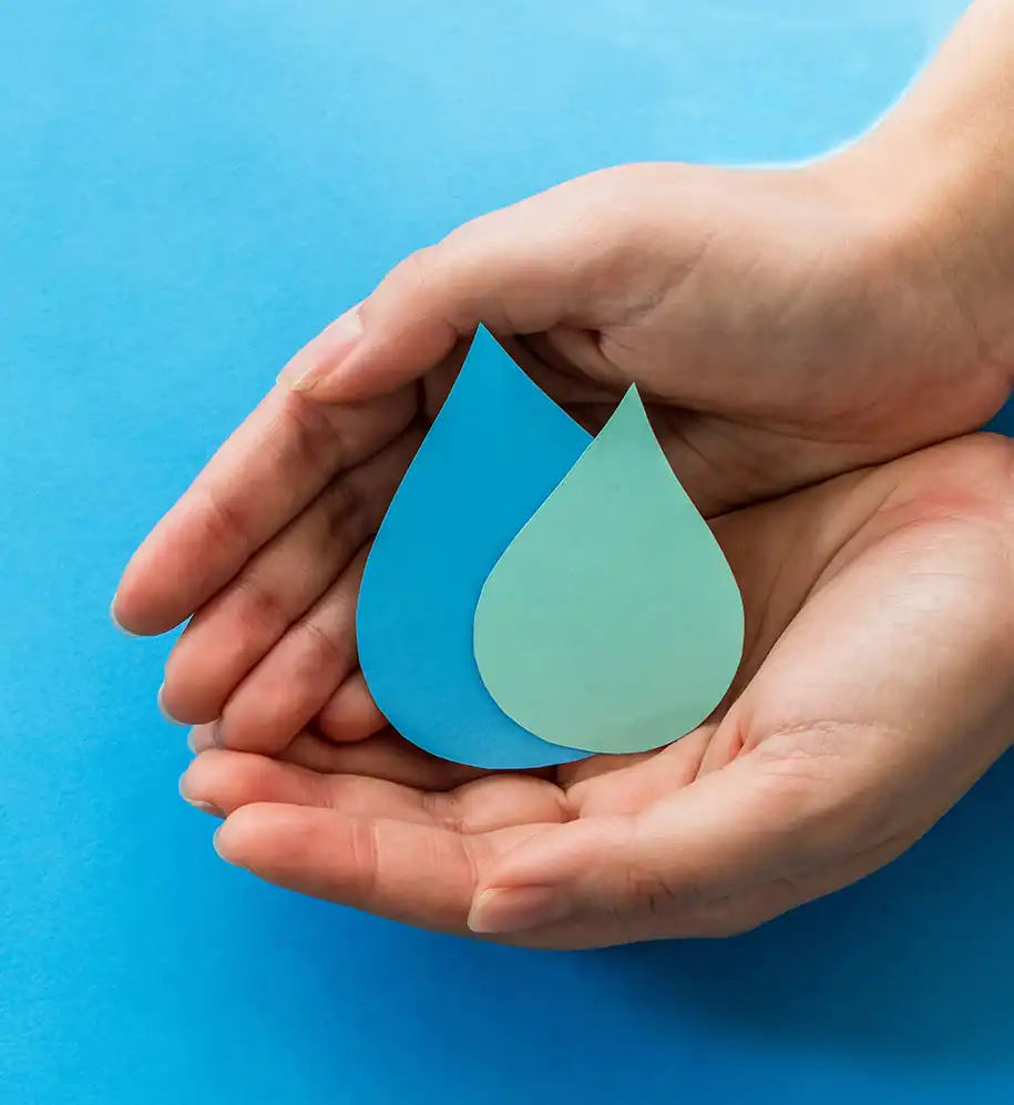 Zwei Hände halten zwei Wassertropfen aus Papier als Symbol für Wassersparen