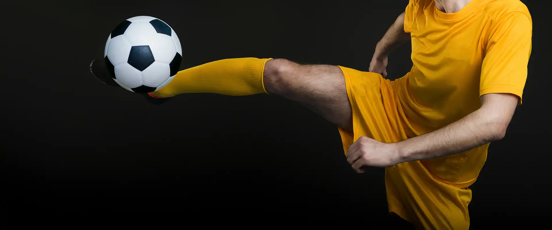 Fußballspieler in gelber Sportkleidung mit Fußball