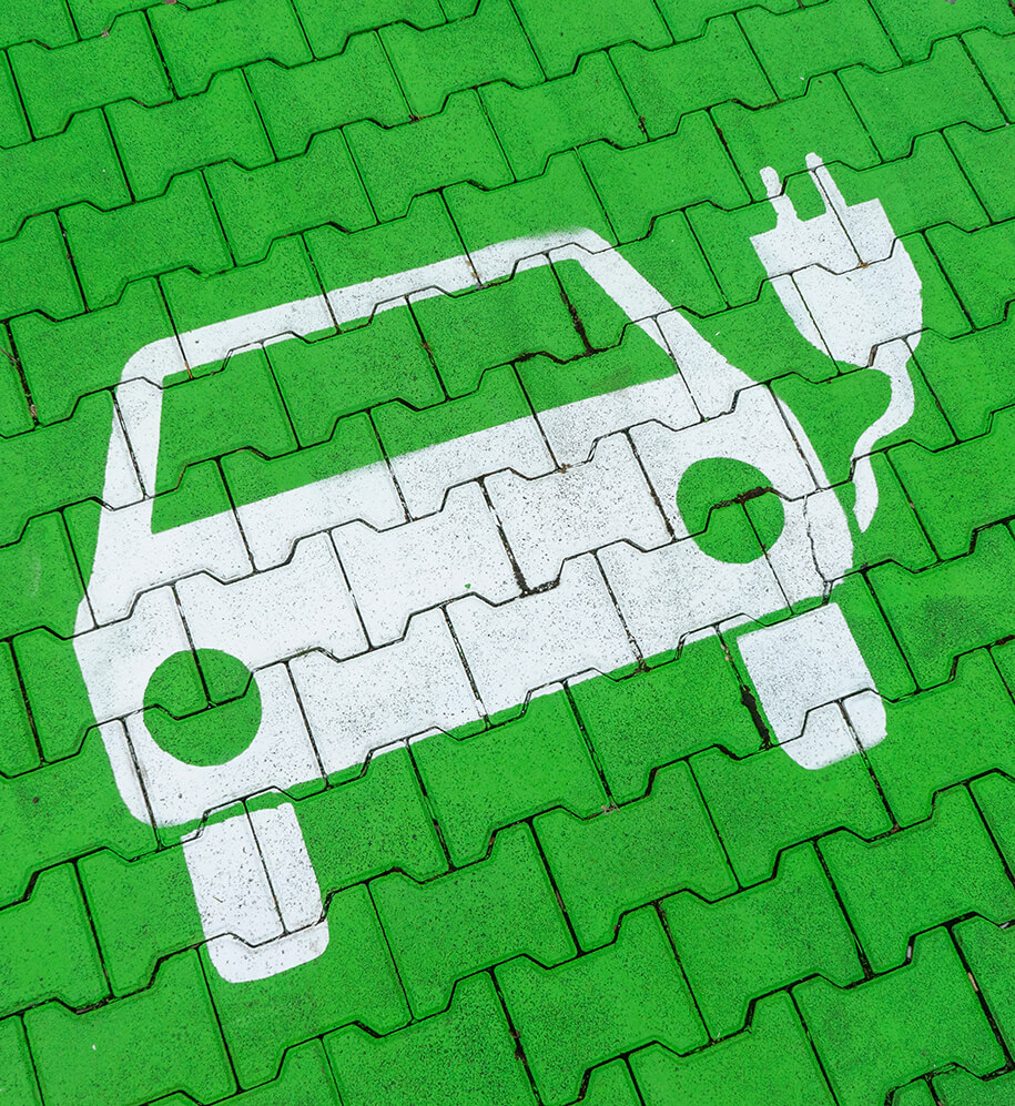 Elektroauto Symbol auf grünem Gehweg